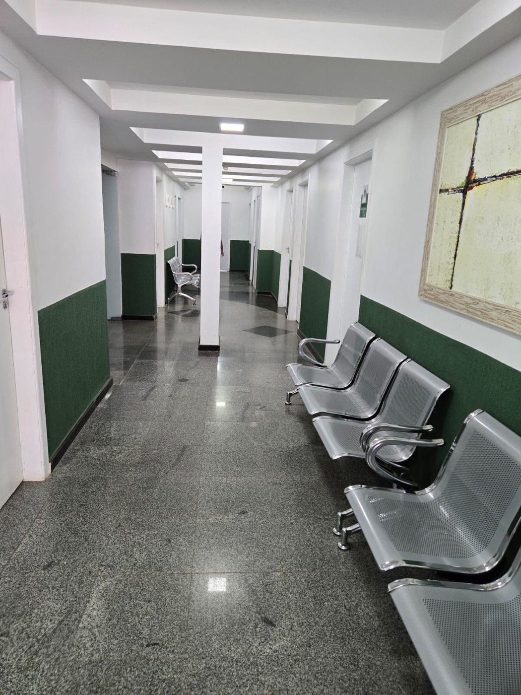 Corredor dos consultórios do Centro Médico Nexo, com cadeiras dos dois lados